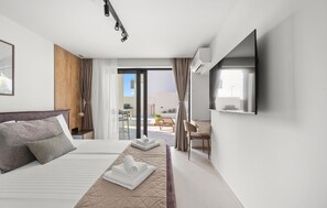 Ein Hotelzimmer mit Bett, Fernseher und Blick nach außen.