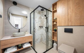 Ein modernes Badezimmer mit freistehender Waschtigung, einer Duschkabine und Holzschränken.