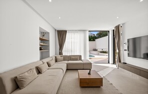 Uma sala de estar moderna com um sofá modular, uma mesa de centro e uma TV de tela plana.