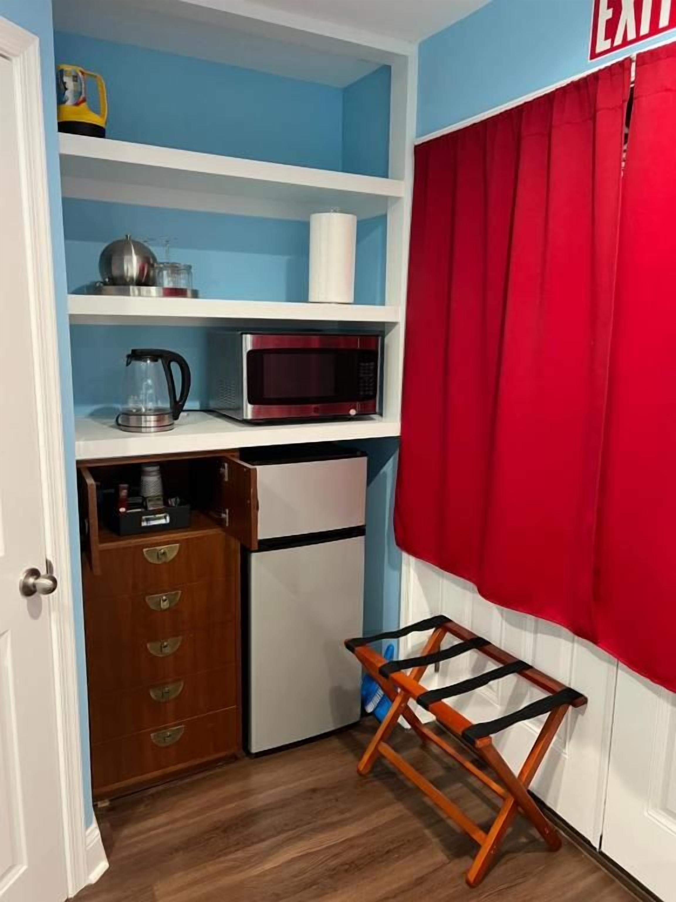 A compact kitchen with a microwave, kettle, and storage drawers.
