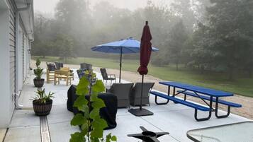 Une terrasse extérieure avec des sièges, une table et un parasol bleu.