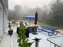 Un patio al aire libre con asientos, una mesa y un paraguas azul.
