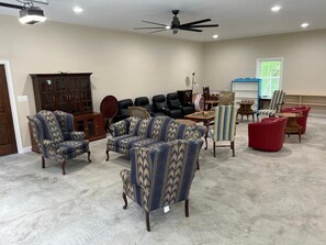 Um quarto amplo, com ventilador de teto, um armário grande, várias cadeiras e uma pequena mesa.
