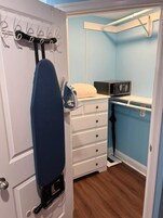 Habitación compacta con plancha incorporada, microondas y cama pequeña.
