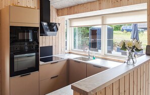 A modern kitchen with a built-in oven, a stainless steel sink, and a window overlooking a garden. - Nice home in Ebeltoft with sauna (Ebeltoft)