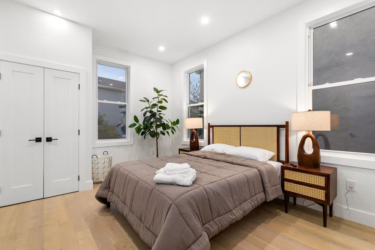 Une chambre à coucher avec un lit, des tables de chevet, une plante et une fenêtre.
