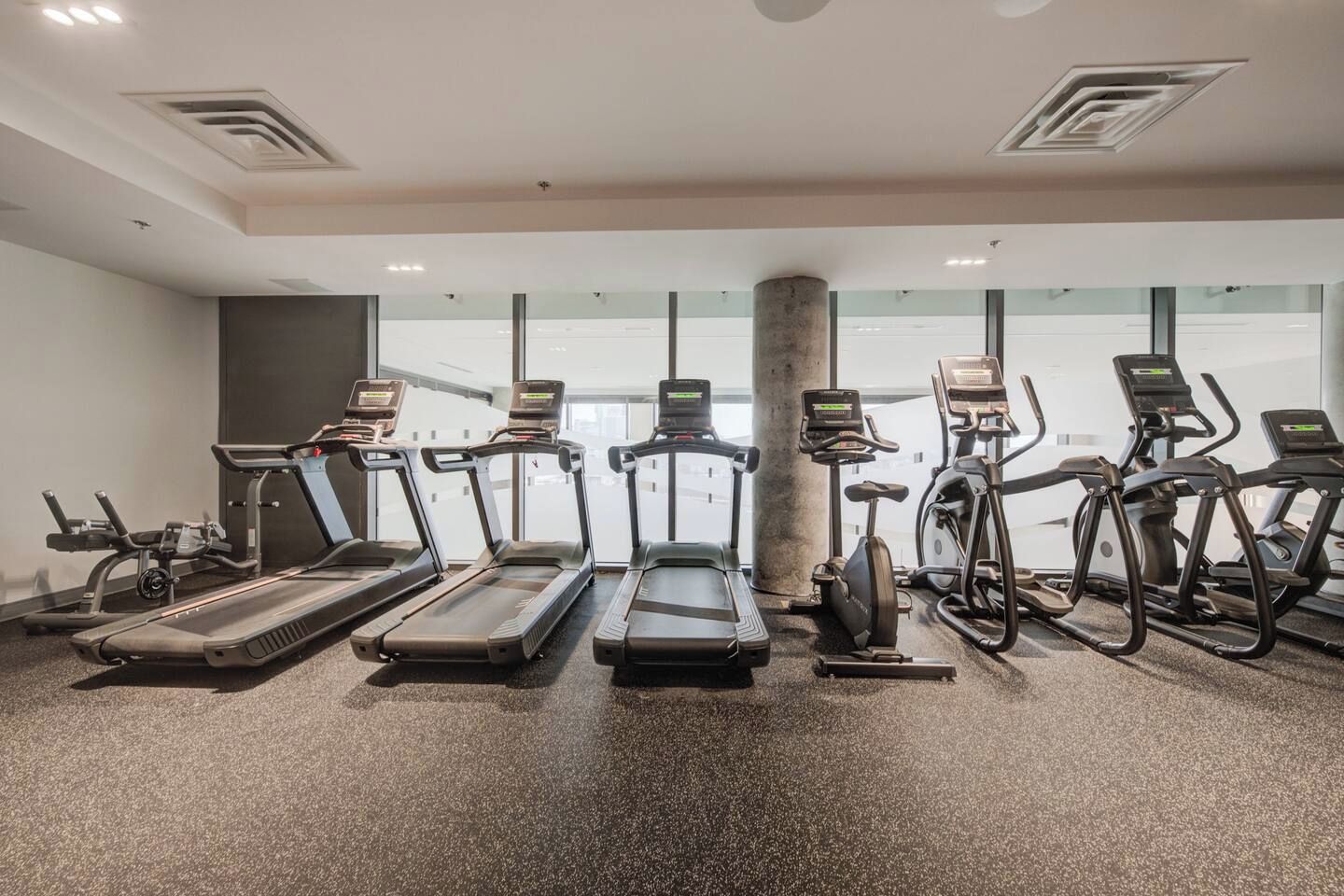 A gym with treadmills, ellipticals, and stationary bikes arranged in rows.