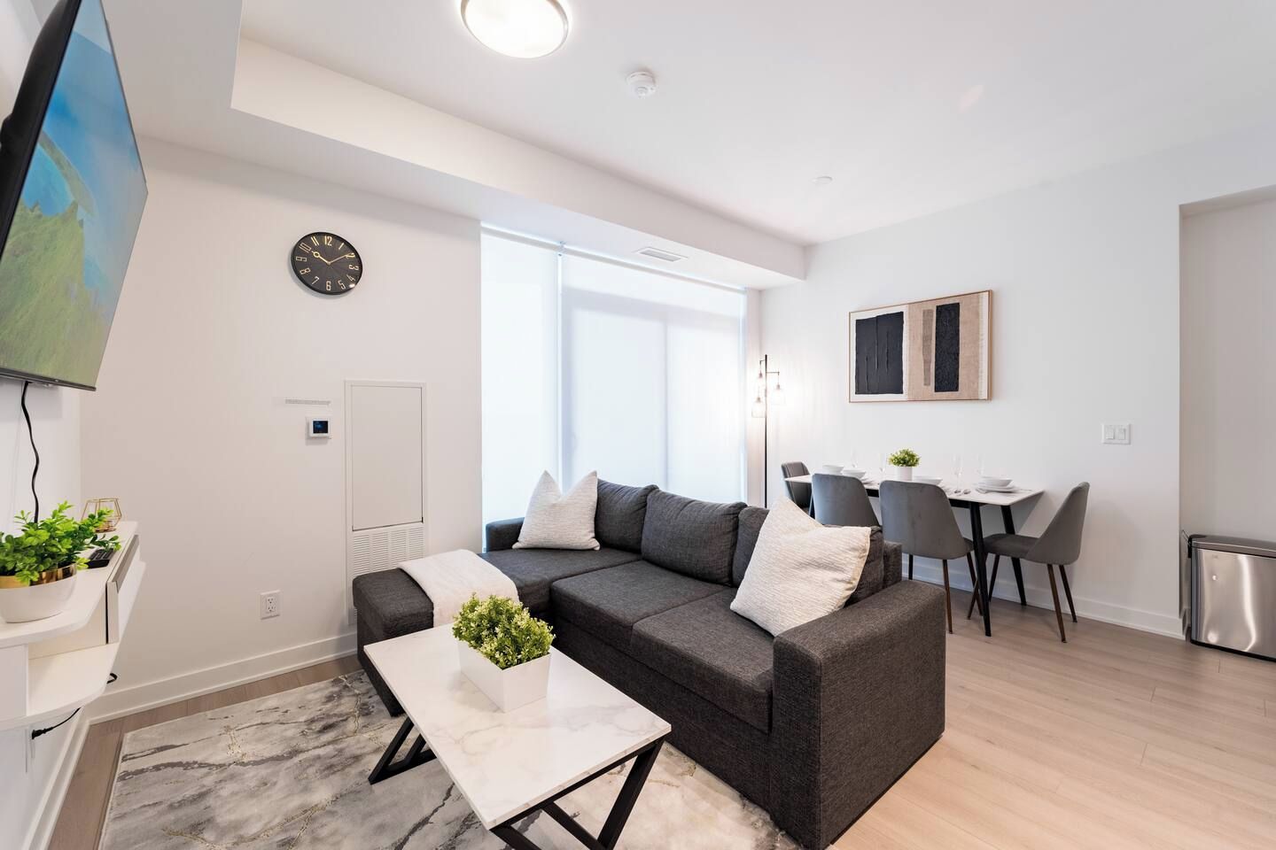 A modern living room with a sofa, coffee table, and a dining area with chairs and a table.