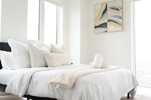 Habitación de hotel con una cama grande, varias almohadas, una manta y vistas por la ventana.