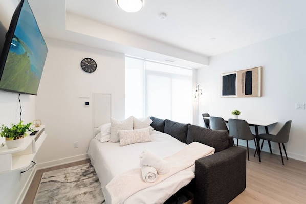 Un dormitorio moderno con una cama, un sofá, un escritorio y un televisor.