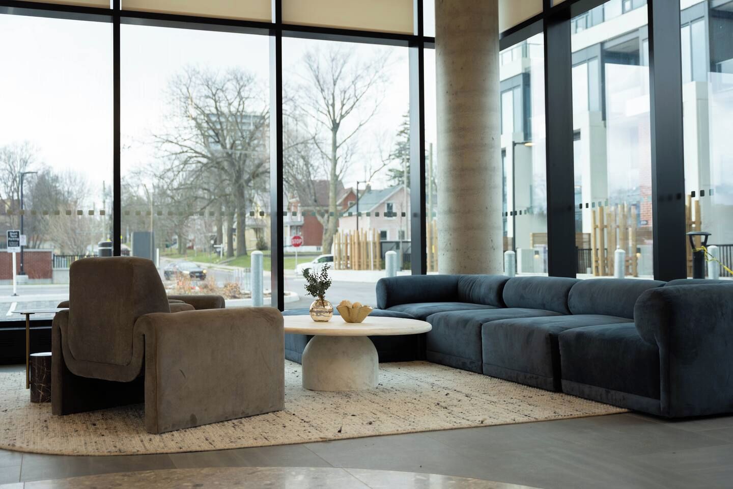 Un salon moderne avec un canapé d’angle, une petite table ronde et un fauteuil.