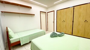 A room with two beds, a wardrobe, and a shelf. - Apartment with Balcony and Parking near Porto da Barra Beach (Salvador)