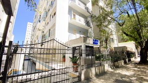 A gated residential building with multiple balconies, a paved entrance area, and a sign indicating the name of the property. - Apartment with Balcony and Parking near Porto da Barra Beach (Salvador)