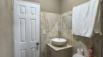 Une salle de bain avec des toilettes, un lavabo, une serviette accrochée au mur et une porte.