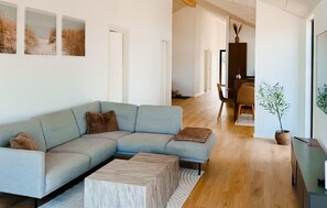 A modern living room with a sectional sofa, a coffee table, and a dining area with chairs and a table. - Stunning home in Odder with sauna (Odder)