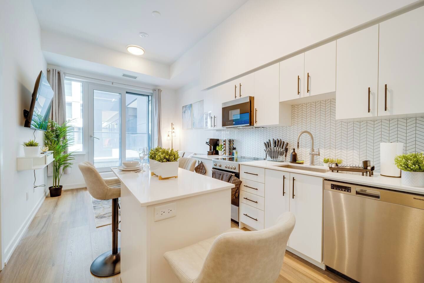 A modern kitchen with white cabinetry, a central island, a microwave, and a dishwasher.
