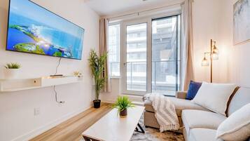 A modern living room with a flat-screen TV, a sofa, a coffee table, and a potted plant.