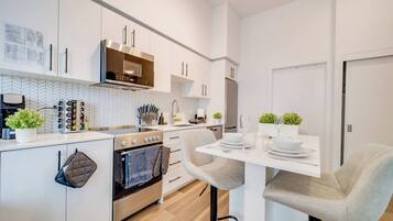 A modern kitchen with white cabinetry, a built-in oven, and a dining area with a table set for two.