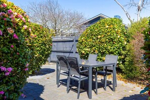 A patio with a table and chairs, surrounded by lush greenery and a building in the background. - Rainbow Haven, Walk to the Lake (Taupō)