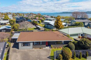 A residential area with houses, a paved driveway, and a body of water in the background. - Rainbow Haven, Walk to the Lake (Taupō)