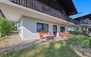 Ein zweistöckiges Gebäude mit Balkon, Sitzgelegenheit im Freien und einem Garten.