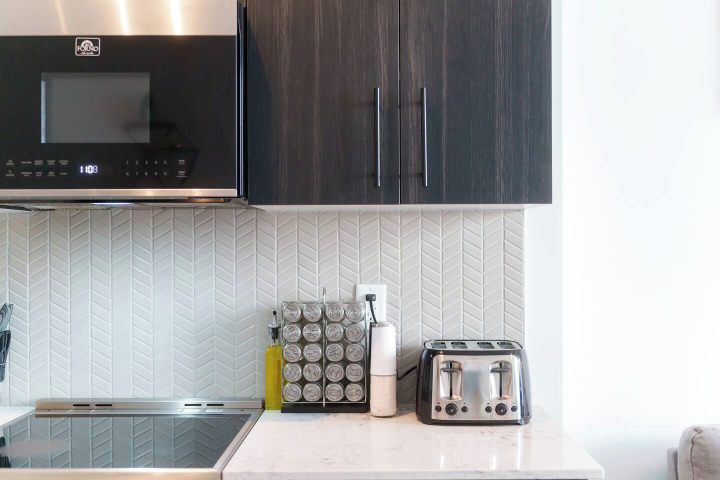 A kitchen with a microwave, toaster, and a set of condiment containers on the counter.
