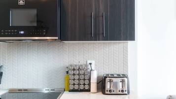 A kitchen with a microwave, toaster, and a set of condiment containers on the counter.