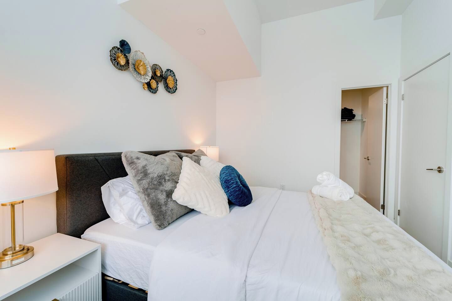 A bedroom with a bed, pillows, a bedside lamp, and a wall art piece.