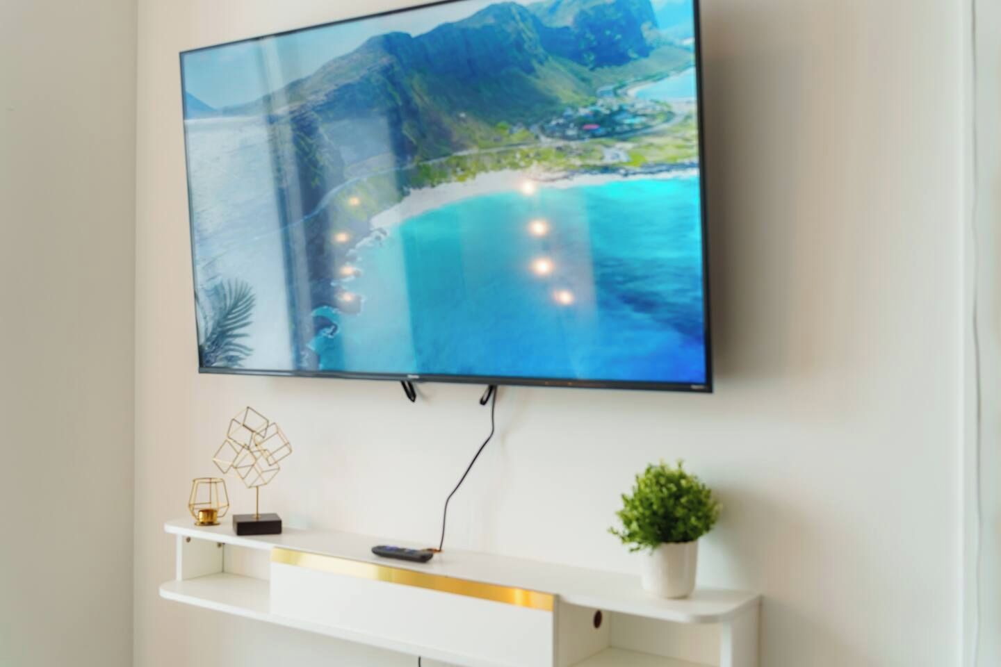 A flat-screen TV mounted on a wall with a scenic coastal landscape displayed on the screen.