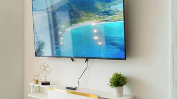 A flat-screen TV mounted on a wall with a scenic coastal landscape displayed on the screen.