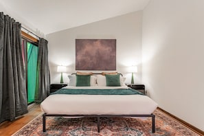 A bedroom with a large bed, two bedside lamps, a green throw blanket, and a large abstract painting on the wall. - NEW: Oaklands Near Shawangunk Mountains (New Paltz)
