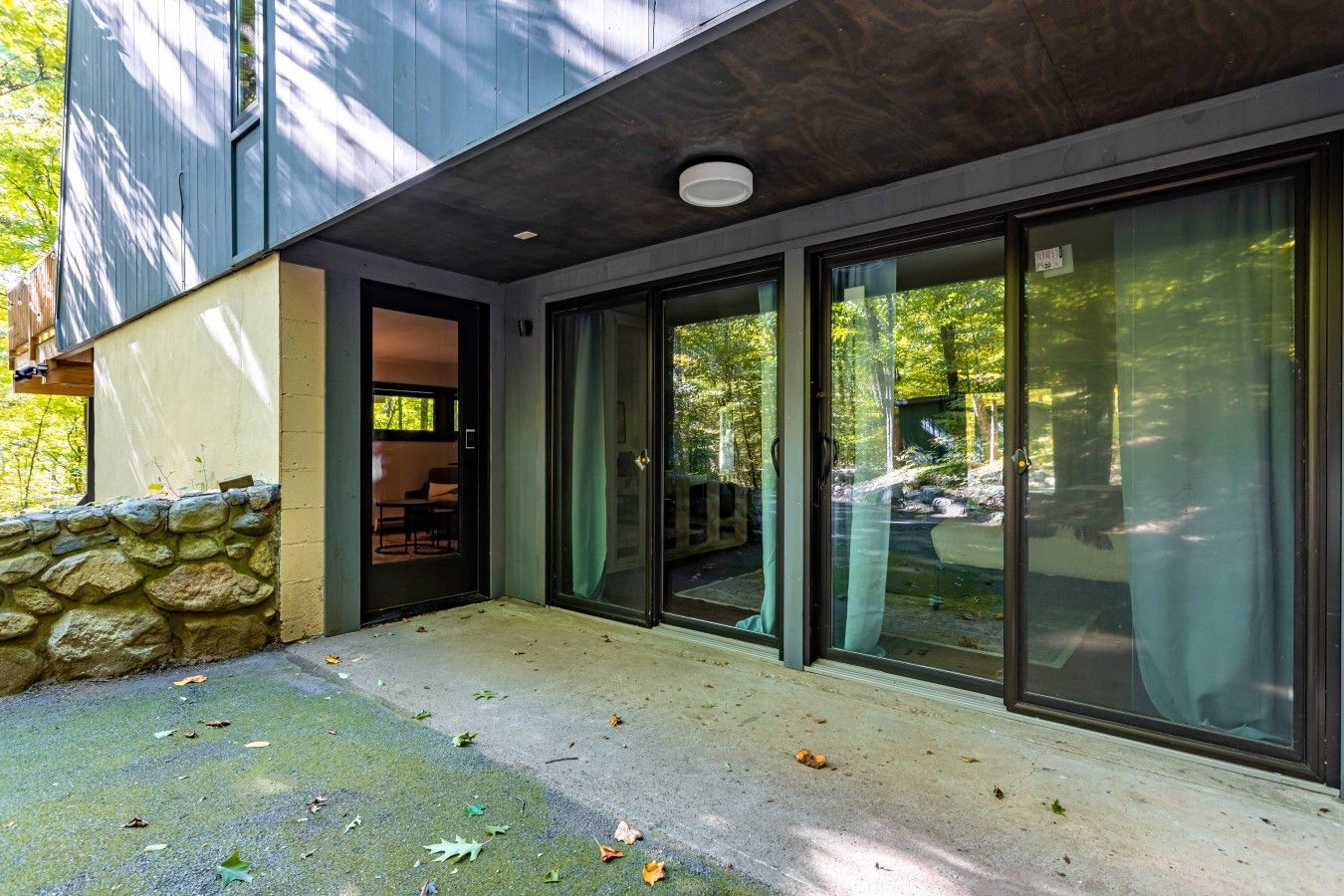 A modern building with a stone wall, a glass door entrance, and a view of the outdoors.