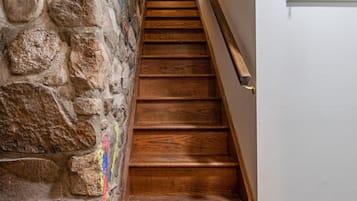 A wooden staircase with a stone wall on one side and a white door on the other.