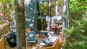 Un espace extérieur abrité, avec une table et des chaises, entouré d’arbres.
