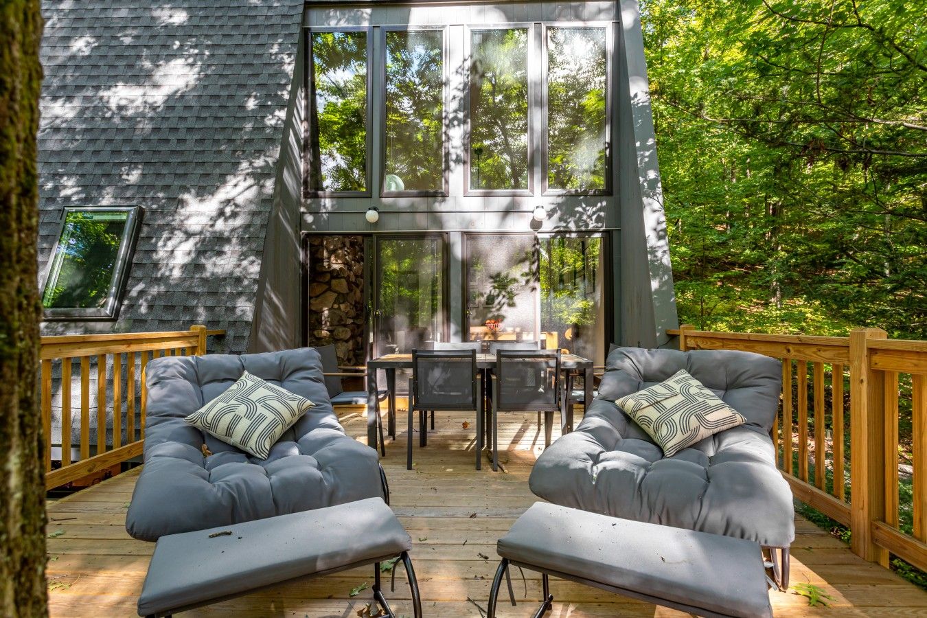 Eine moderne Terrassenanlage mit zwei grauen Sofas, einem Holztisch und einer Steinwand.