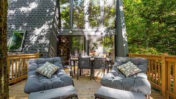 Eine moderne Terrassenanlage mit zwei grauen Sofas, einem Holztisch und einer Steinwand.