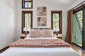 Une chambre à coucher avec un grand lit, deux tables de chevet et trois œuvres d’art encadrées accrochées au mur.