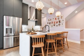 Black cabinets, white island, and a photo gallery wall turn the kitchen into the heart where the group gathers and lingers - Swiftie-themed Nashville house, fire pit, 2-car garage, sleeps 20 near Geodis (Nashville)