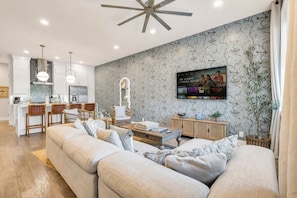 Een moderne woonkamer met een bank, een salontafel en een aan de muur bevestigde televisie.