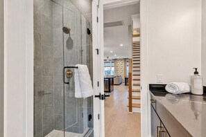 Grey tile shower with a glass door and plenty of elbow room. Four bedrooms means multiple showers running in the morning, and this one never feels rushed - Nashville rooftop retreat with fire pit, garage, sleeps 12 near Geodis Park (Nashville)