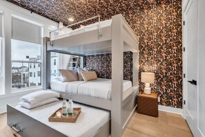 A bunk bed room with a city view, a patterned wallpaper, and a bedside table with a lamp. - Nashville rooftop retreat with fire pit, garage, sleeps 12 near Geodis Park (Nashville)