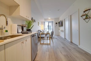 A modern kitchen with a dining area, wooden flooring, and a view to the outside. - Modern Condo in Central KW w/ Gym (Kitchener)