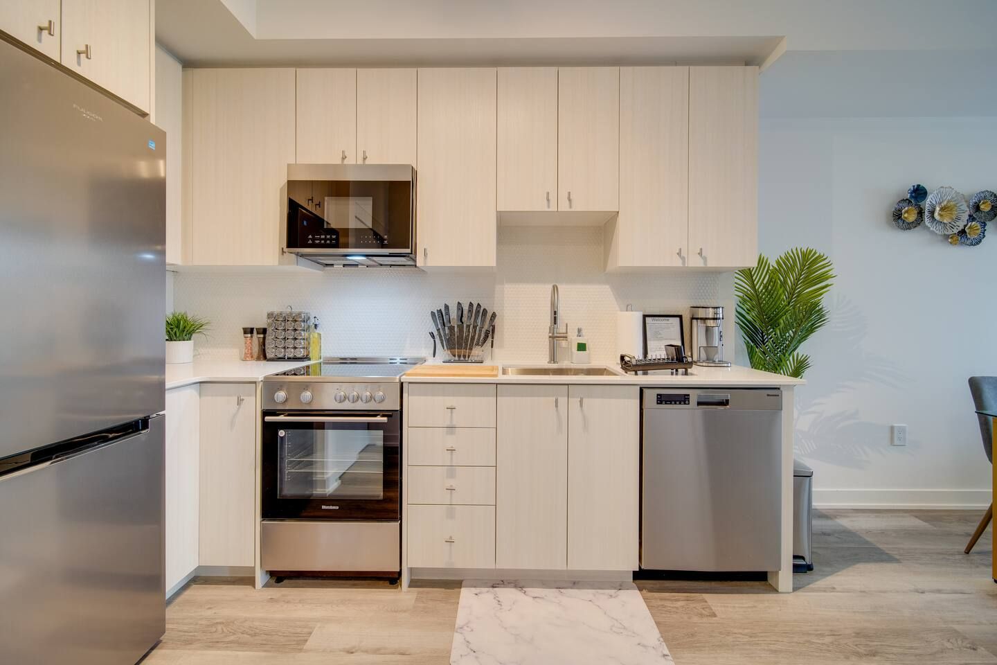 Een moderne keuken met roestvrijstalen apparatuur, witte kasten en een marmeren aanrecht.
