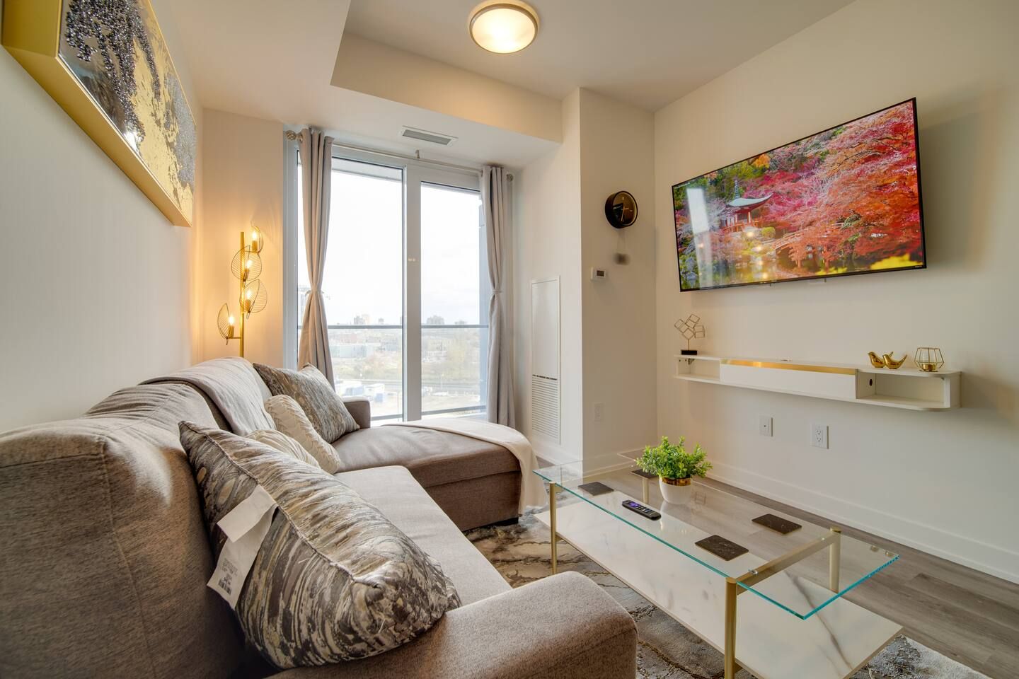 A modern living room with a sectional sofa, a glass coffee table, and a large painting on the wall.