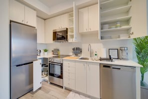 A modern kitchen with stainless steel appliances, white cabinetry, and a built-in oven. - Modern Condo in Central KW w/ Gym (Kitchener)