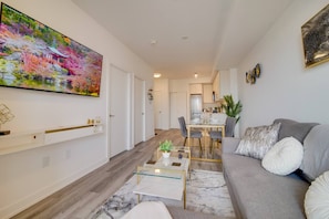 A modern living room with a sofa, coffee table, and a dining area. - Modern Condo in Central KW w/ Gym (Kitchener)