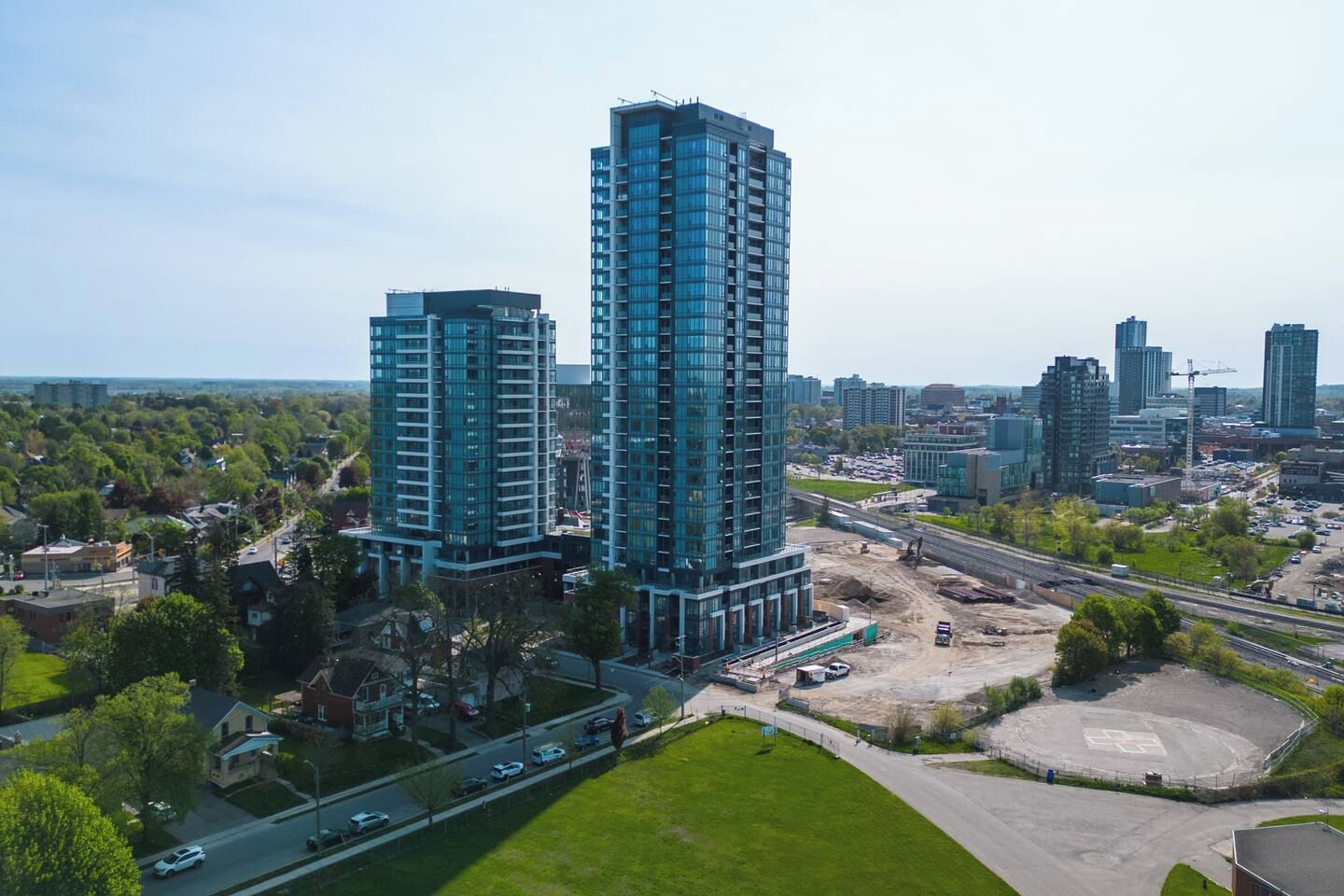 A high-rise building with a modern glass facade, surrounded by a mix of residential and commercial buildings, and a highway in the background.