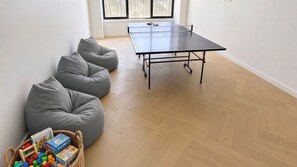 A room with a ping pong table, grey bean bag chairs, and a basket of children's toys. - 6 bedrooms sleeping up to 20 guests in Bundalong. (Bundalong)