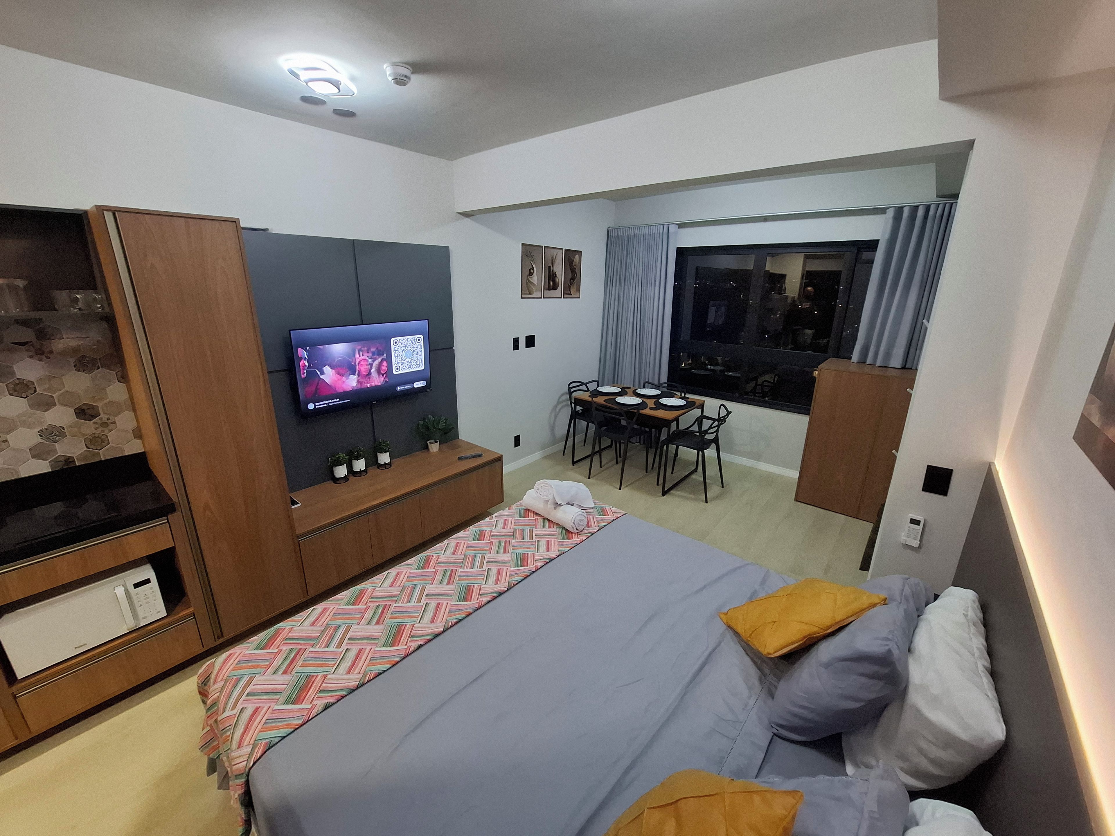 Une chambre moderne équipée d’un lit, d’une télévision, d’un coin repas et offrant une vue sur l’extérieur.