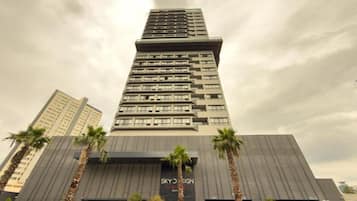 Un edificio de hotel alto con un diseño moderno, que presenta una entrada destacada y un letrero que dice 'SKY DESIGN HOTEL'.